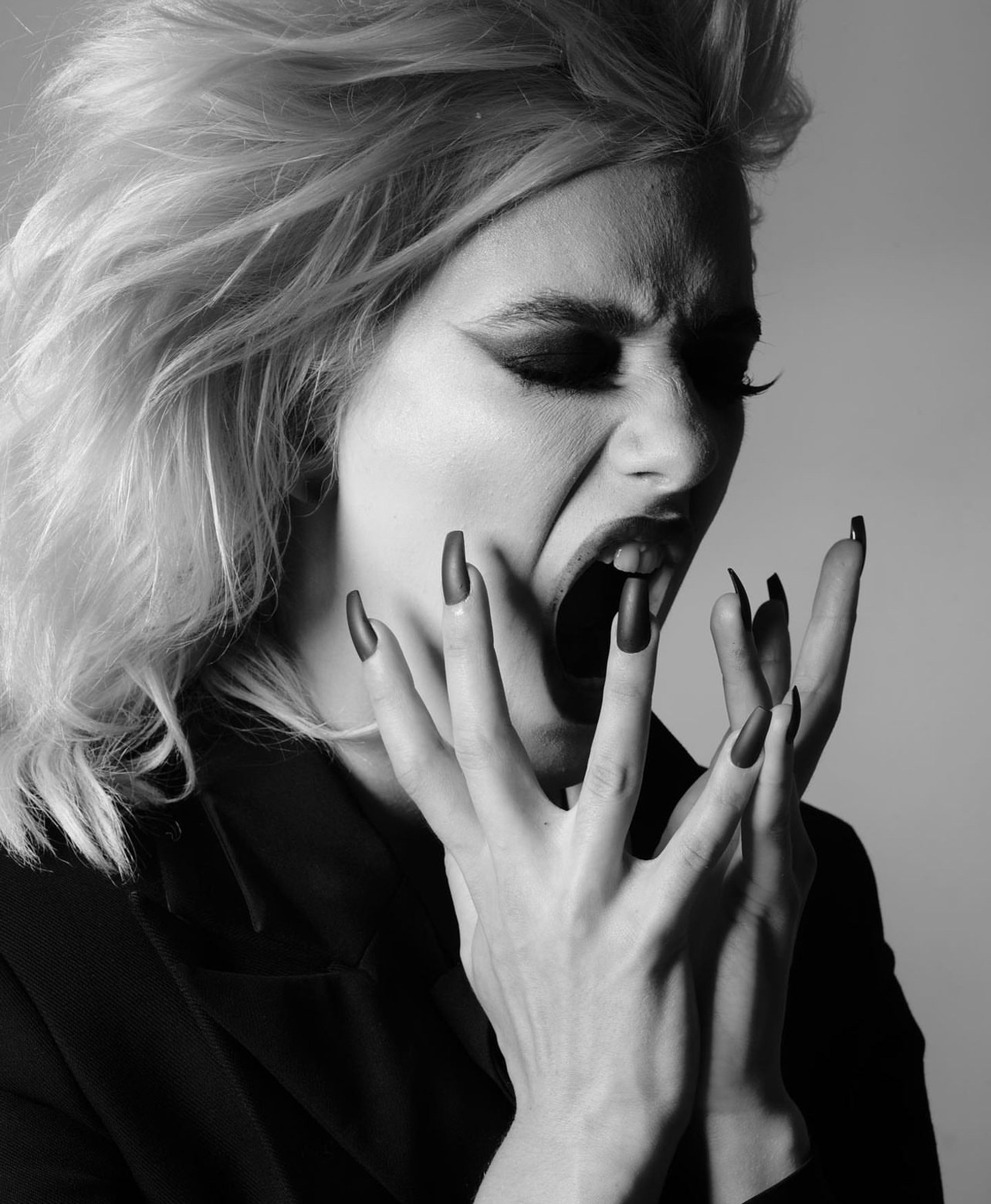 Close black and white beauty frame of Dawn Muensterman with long lacquered nails framing her open mouth