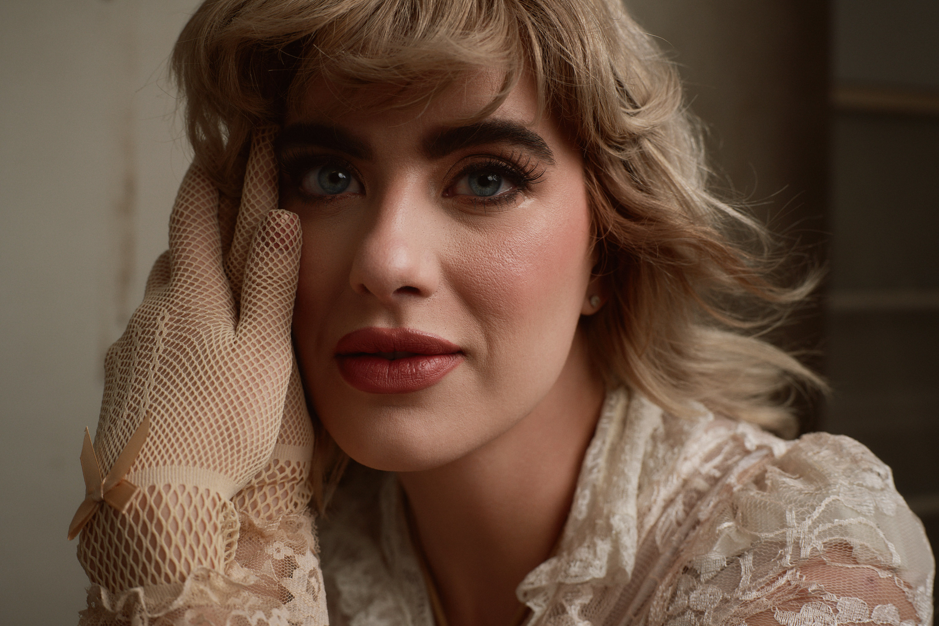 Soft-lit beauty portrait of Dawn Muensterman in lace and fishnet gloves with a red lip and cropped blonde waves