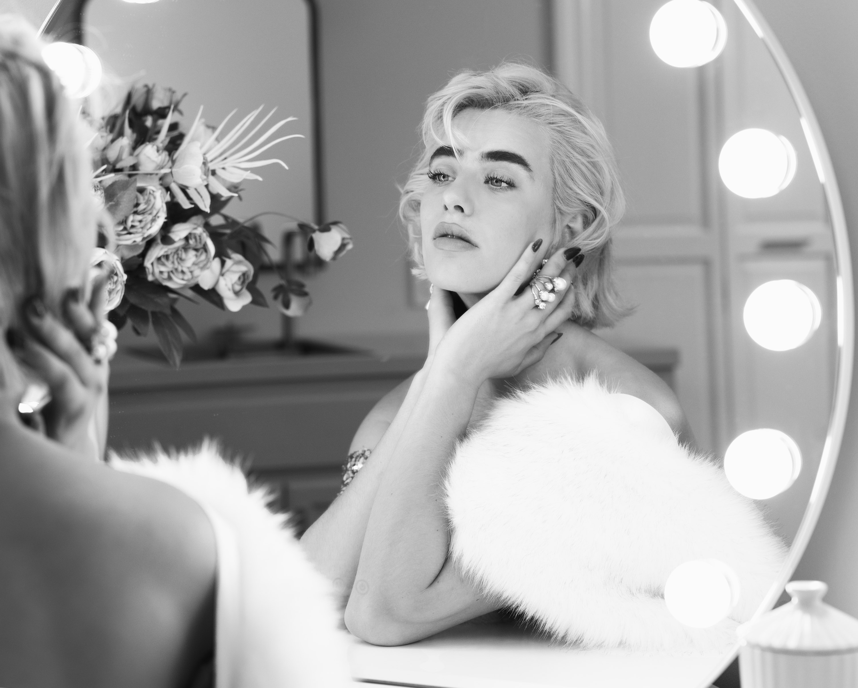 Dawn Muensterman in white fur at a lit vanity mirror, black and white