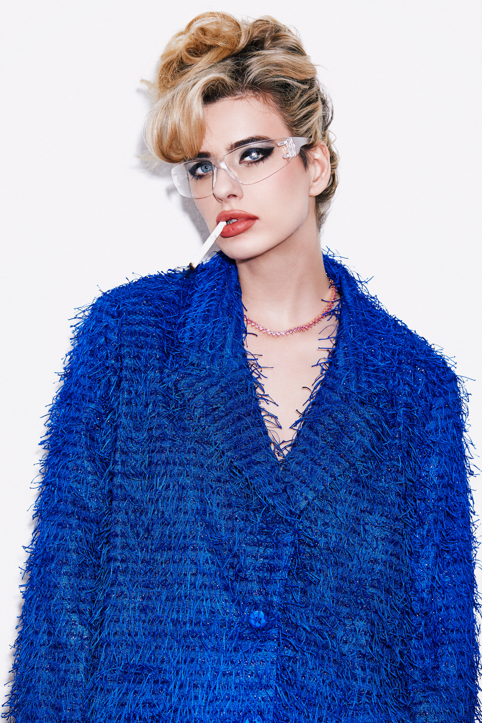 Dawn Muensterman in an oversized cobalt fringed coat with a fine pink chain necklace