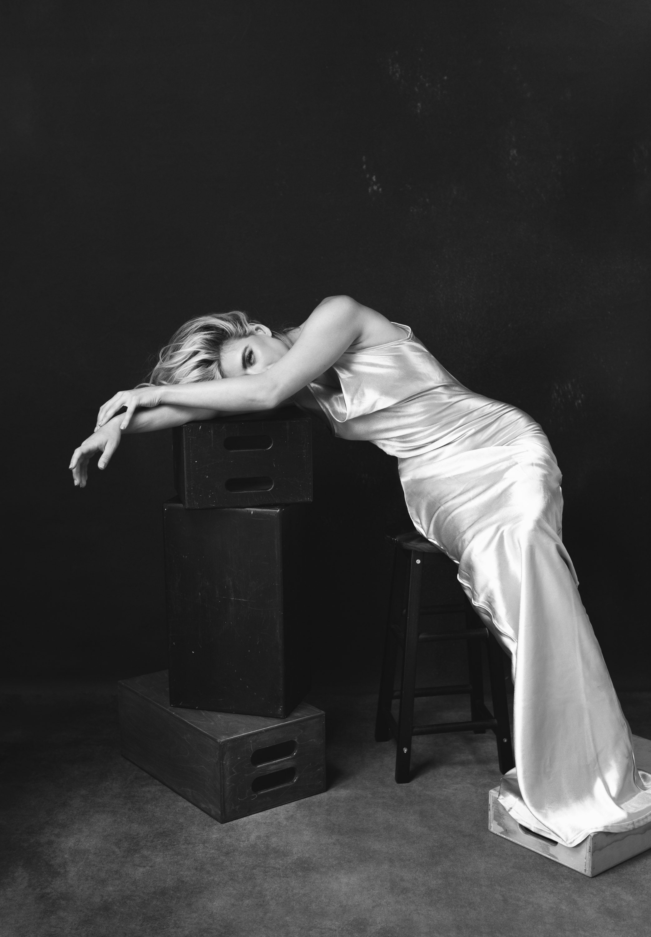 Dawn Muensterman in a white satin gown draped across studio blocks, black and white
